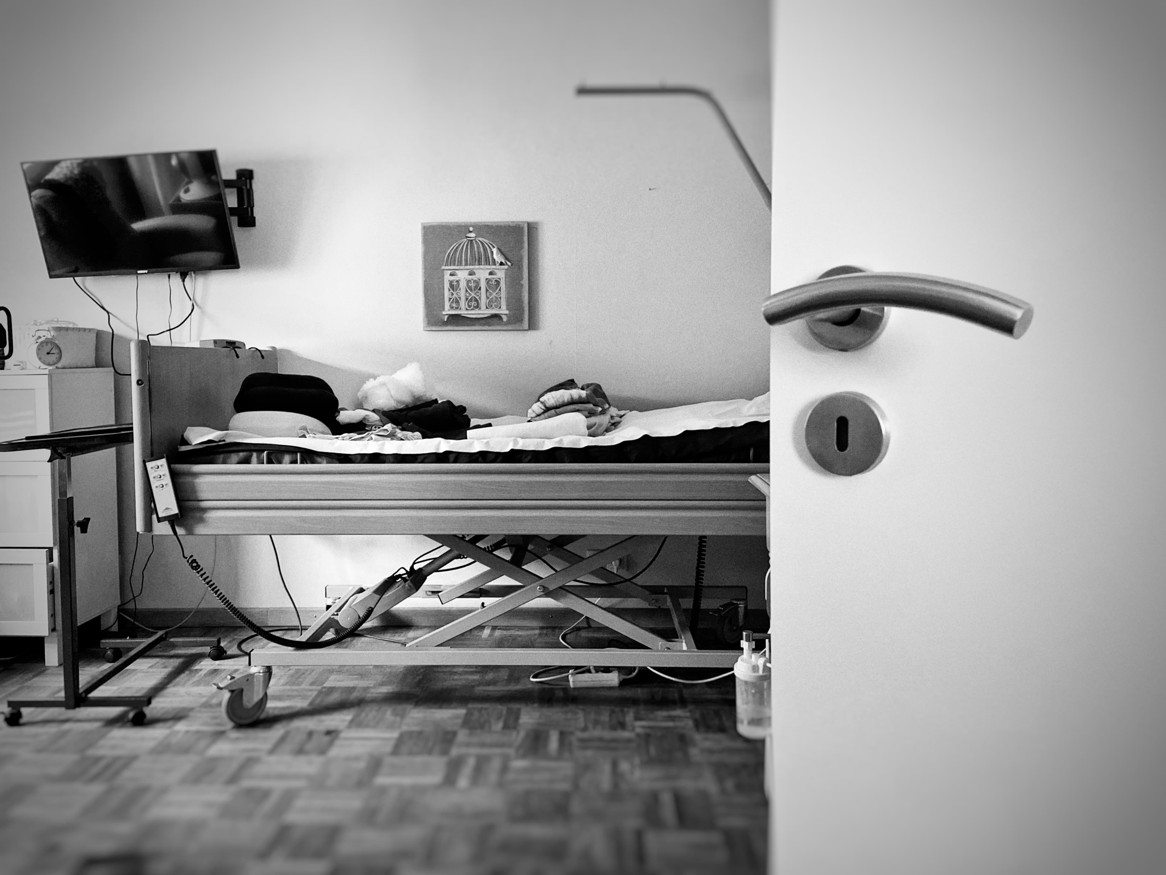 A quiet room seen through an open door, with an empty care bed